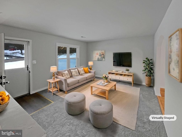 living room with dark colored carpet and plenty of natural light