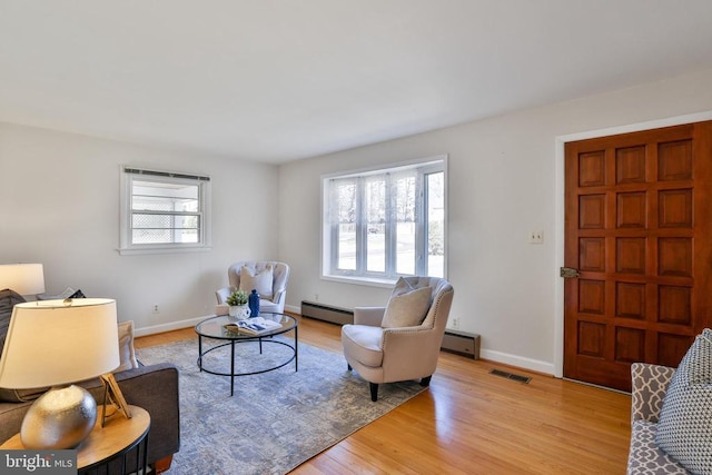 living room with light wood-type flooring, plenty of natural light, and a baseboard radiator