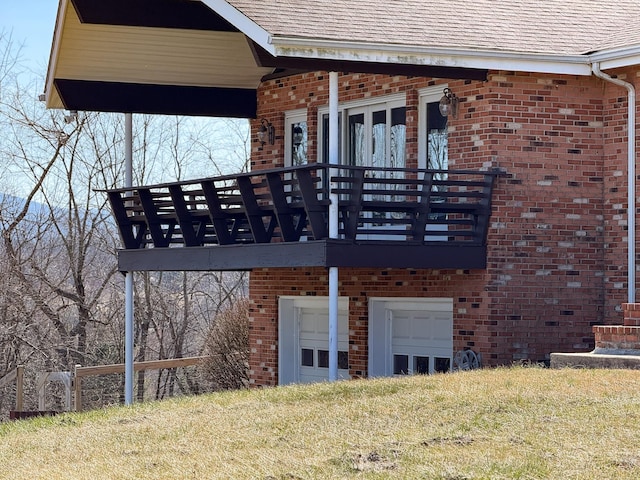 exterior space with brick siding, a lawn, an attached garage, and a shingled roof