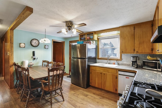 kitchen featuring light wood finished floors, light countertops, appliances with stainless steel finishes, a sink, and a textured ceiling