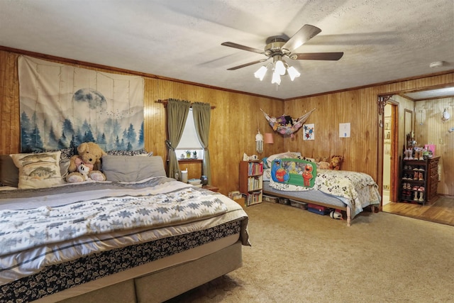 bedroom featuring carpet floors, ornamental molding, ceiling fan, a textured ceiling, and wooden walls