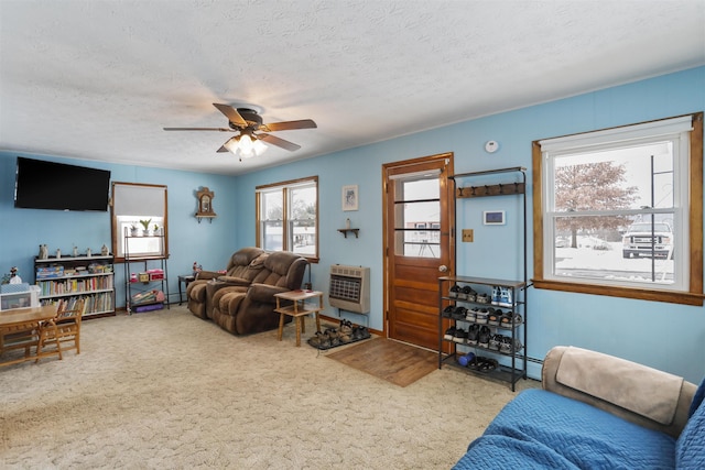 living room featuring carpet flooring, ceiling fan, a textured ceiling, and heating unit