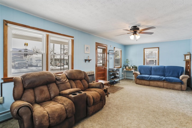 living area featuring baseboard heating, an AC wall unit, carpet flooring, ceiling fan, and a textured ceiling