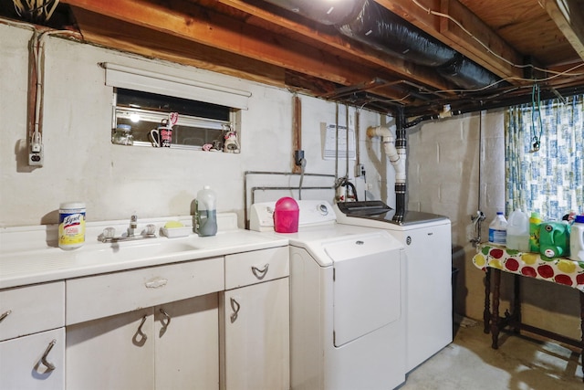 clothes washing area with a sink, cabinet space, and washer and dryer