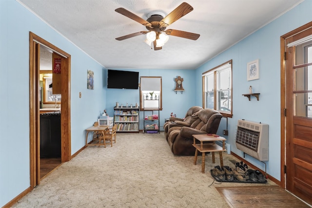 living room with a textured ceiling, a ceiling fan, baseboards, heating unit, and carpet