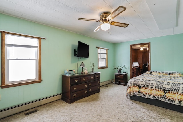 bedroom with a baseboard heating unit, light colored carpet, visible vents, and a ceiling fan