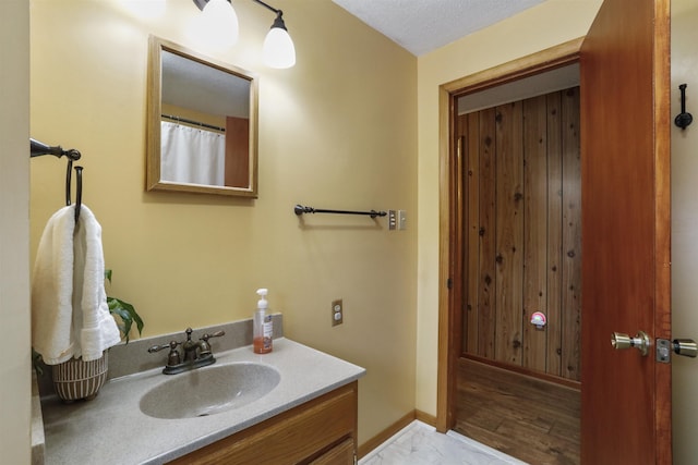 bathroom featuring baseboards, a textured ceiling, and vanity