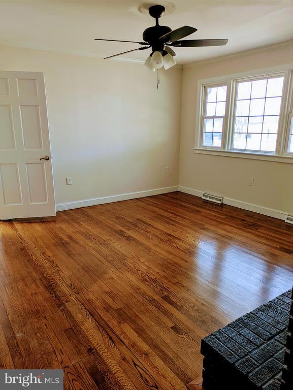 unfurnished room with wood finished floors, baseboards, visible vents, ceiling fan, and ornamental molding