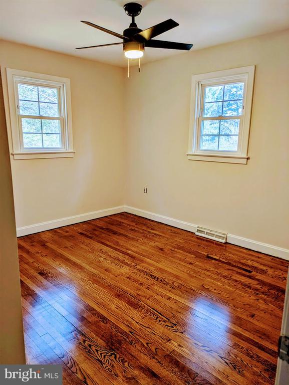 spare room with visible vents, baseboards, a ceiling fan, and hardwood / wood-style flooring