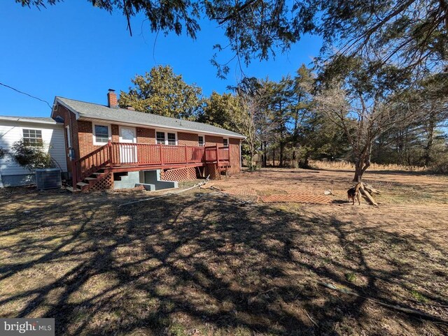 rear view of house with brick siding, a yard, a chimney, and a deck