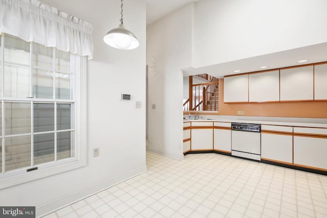 kitchen featuring hanging light fixtures, white cabinets, dishwasher, and a high ceiling