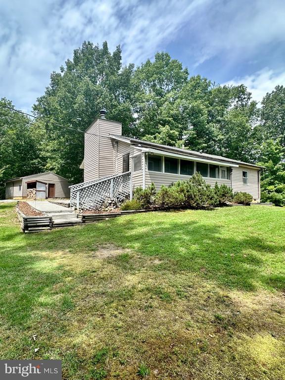 rear view of house featuring a garage, an outdoor structure, and a lawn