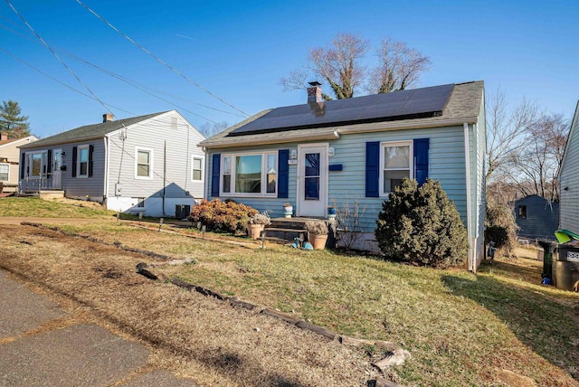 bungalow-style home featuring a front lawn and roof mounted solar panels