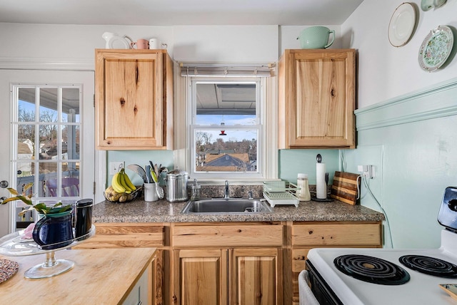 kitchen with a sink, light brown cabinets, and white range with electric cooktop