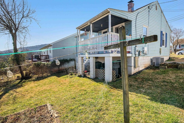 back of house with stairs, central AC unit, a lawn, and a chimney