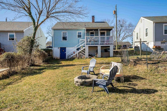 back of property featuring fence, stairway, an outdoor fire pit, a lawn, and a chimney