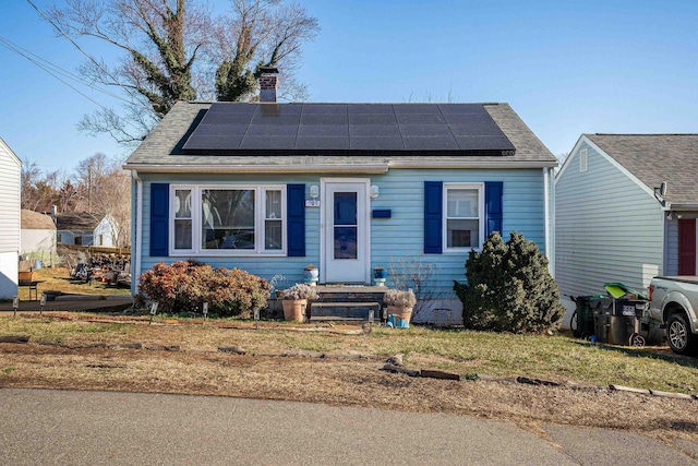 bungalow-style home featuring solar panels, entry steps, and a chimney