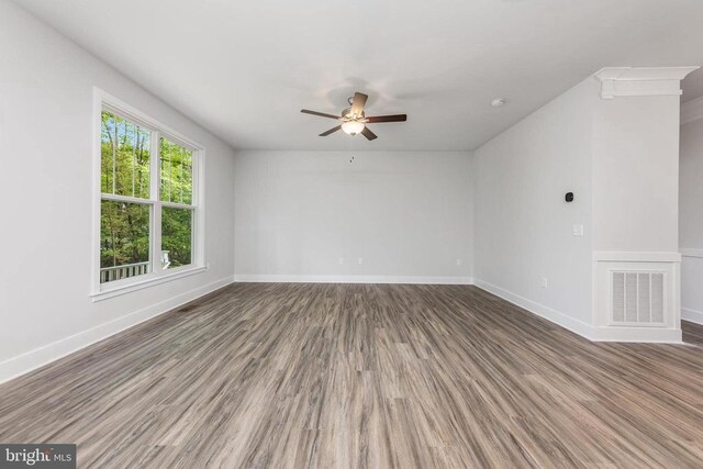 unfurnished room with a ceiling fan, wood finished floors, visible vents, and baseboards