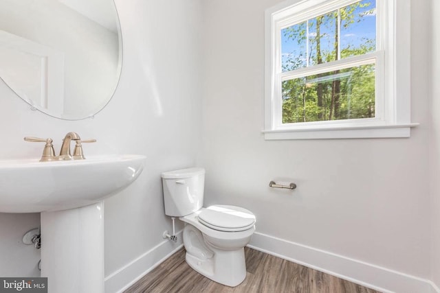 half bathroom featuring baseboards, toilet, and wood finished floors