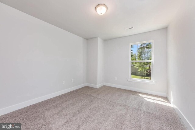 carpeted spare room with visible vents and baseboards