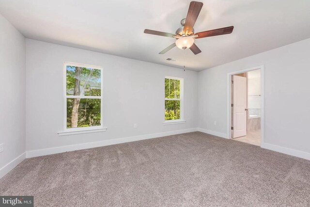 carpeted spare room featuring a ceiling fan and baseboards