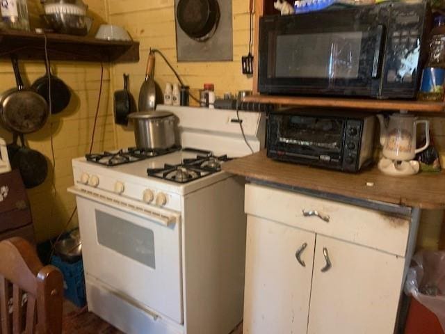 kitchen with white cabinetry and white range with gas stovetop