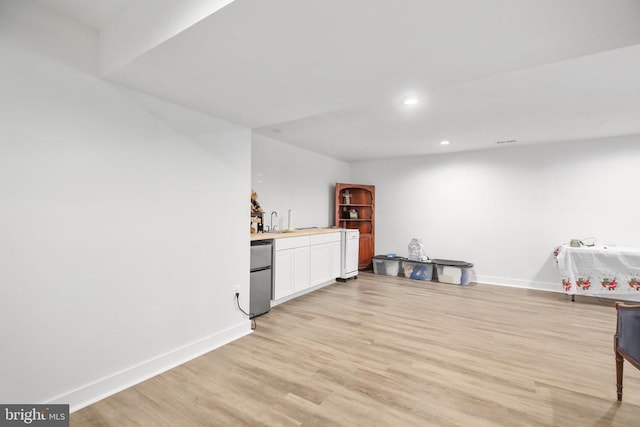 interior space with wood counters, sink, white cabinetry, dishwasher, and light hardwood / wood-style floors