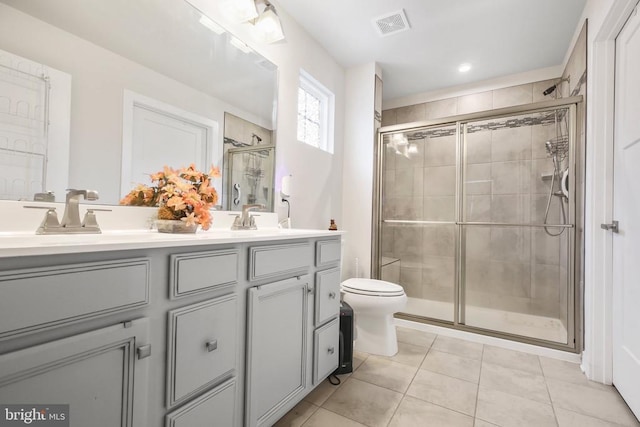 bathroom with vanity, tile patterned flooring, a shower with door, and toilet