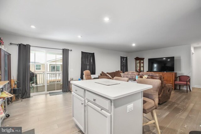 kitchen featuring white cabinetry, light hardwood / wood-style floors, a kitchen breakfast bar, and a kitchen island