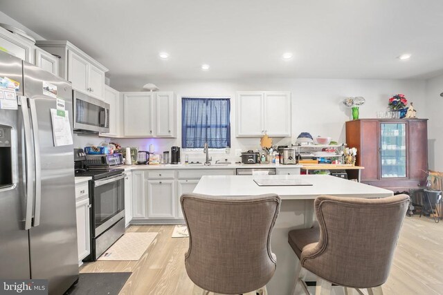 kitchen with appliances with stainless steel finishes, sink, a kitchen island, and white cabinets