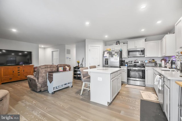 kitchen featuring white cabinetry, appliances with stainless steel finishes, a center island, and sink