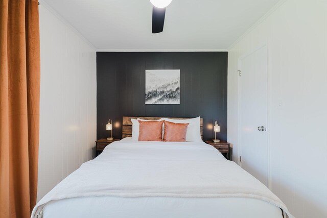 bedroom with crown molding, a ceiling fan, and a decorative wall