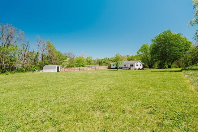 view of yard featuring fence, an outbuilding, and a rural view