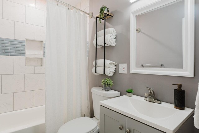 bathroom featuring vanity, shower / tub combo with curtain, and toilet