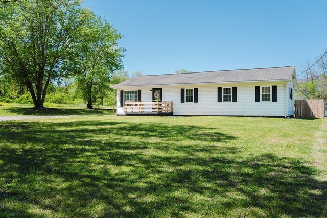 ranch-style home featuring fence, a wooden deck, and a front yard