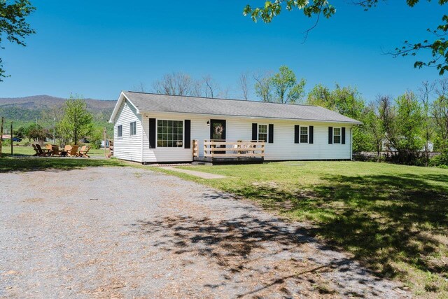 ranch-style home with a deck with mountain view and a front yard