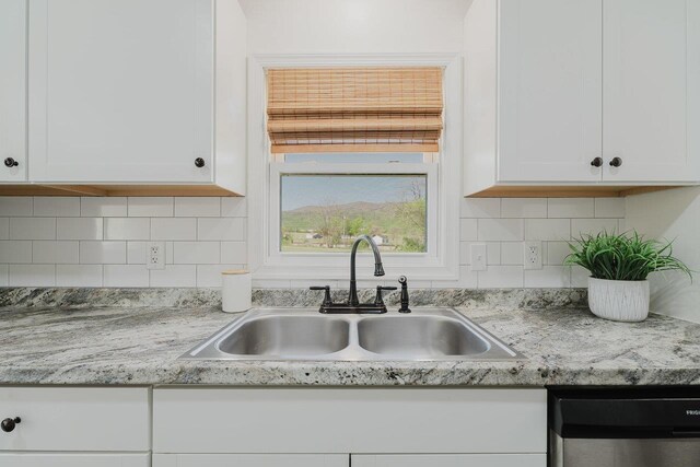 kitchen with white cabinets, light countertops, a sink, and dishwasher