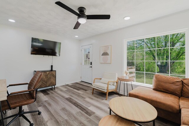 living room featuring a ceiling fan, baseboards, a healthy amount of sunlight, and light wood-style floors