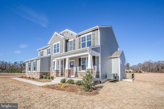 craftsman inspired home featuring covered porch, central AC unit, and stone siding