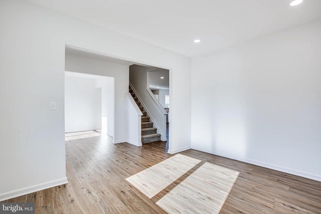 unfurnished room featuring stairway, wood finished floors, and baseboards