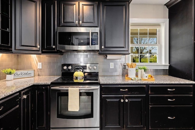 kitchen featuring dark cabinetry, appliances with stainless steel finishes, and tasteful backsplash