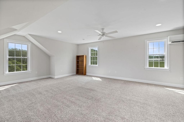 bonus room with an AC wall unit, baseboards, and a wealth of natural light