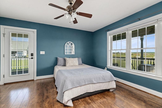bedroom with baseboards, hardwood / wood-style floors, and multiple windows