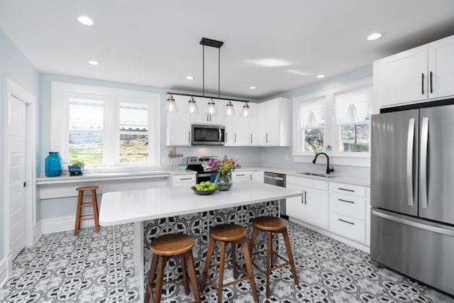 kitchen featuring a sink, a kitchen breakfast bar, stainless steel appliances, white cabinets, and light countertops