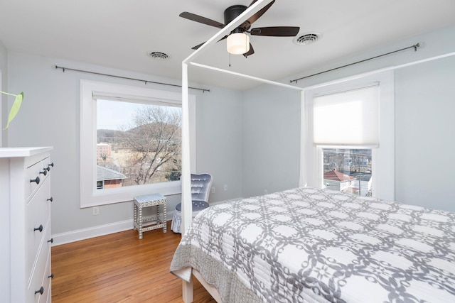 bedroom featuring ceiling fan, baseboards, visible vents, and light wood-type flooring