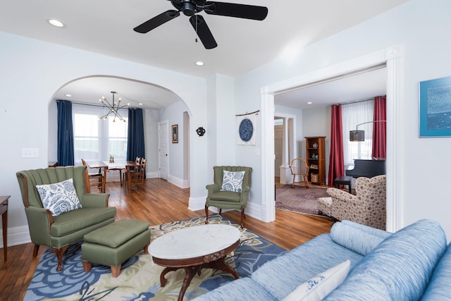 living room featuring arched walkways, recessed lighting, baseboards, and wood finished floors