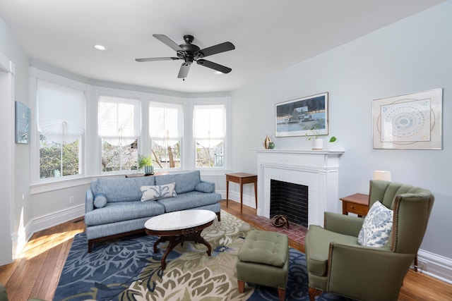 living area featuring a fireplace with flush hearth, wood finished floors, and baseboards