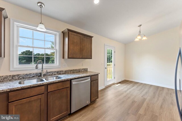 kitchen featuring pendant lighting, dishwasher, sink, light stone counters, and light hardwood / wood-style flooring