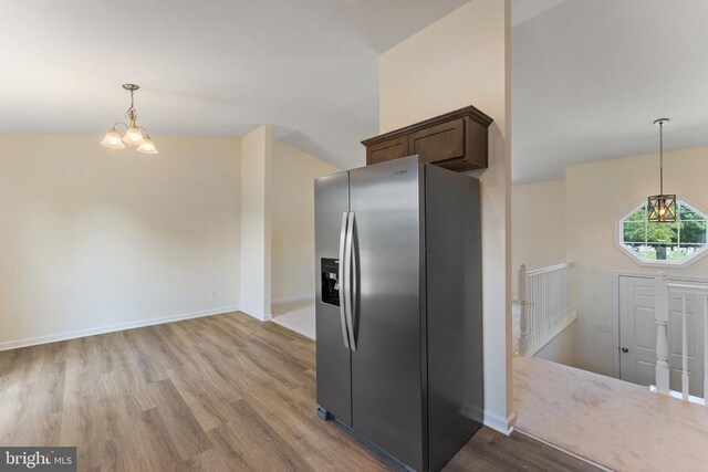 kitchen featuring dark brown cabinets, light hardwood / wood-style flooring, stainless steel fridge, a notable chandelier, and pendant lighting