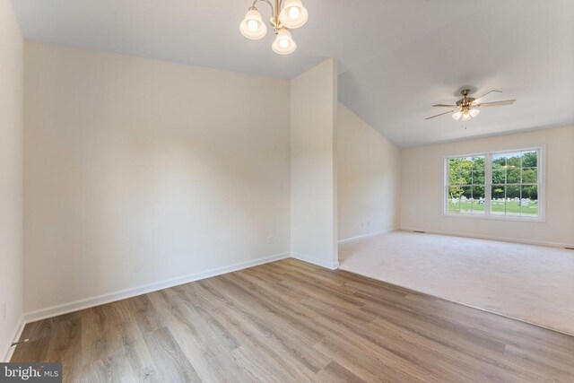 spare room featuring ceiling fan with notable chandelier and light hardwood / wood-style flooring